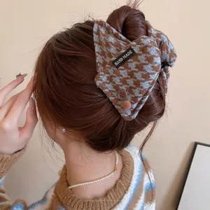 Brown and blue plaid acrylic hair claw clip with buttons shown on woman's hair