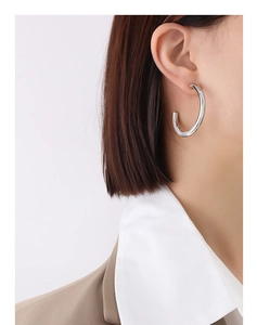 Macro detail of large C-shaped hollow hoop earring in polished silver minimalist design