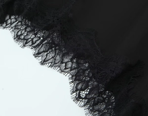 Detailed close-up of delicate eyelash lace trim on a black asymmetric slip dress