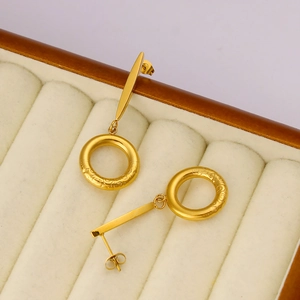 Detail of 18K gold-plated earrings with engraved hoops on a beige velvet jewelry box