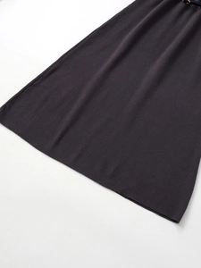 Detail of dark grey ribbed knit fabric hem on a long dress with smooth texture