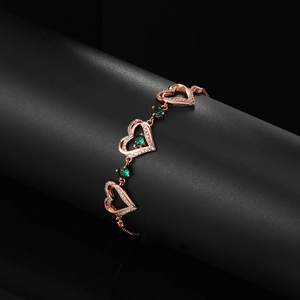 Macro shot of rose gold heart bracelet featuring emerald green zircon and pavé setting