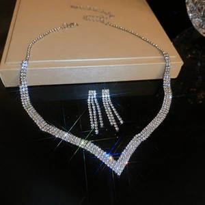 Detailed view of silver V-shaped necklace and matching rhinestone tassel earrings set