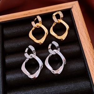 Nahaufnahme geometrischer Rauten-Ohrringe mit Zirkonia-Steinen in Gold und Silber-Finish