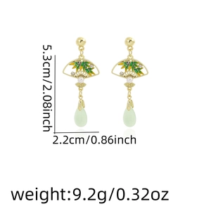 Detail of fan-shaped bamboo earrings with green enamel and size measurement display