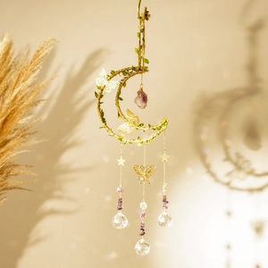 Detail of moon-shaped wind chime with hemp rope, green leaves and crystal prisms