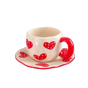 Handmade ceramic coffee cup and saucer set with red heart patterns and irregular edges