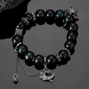 Close-up of beaded dragon bracelet with green ghost stones and silver charms