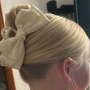 Side view of large cream satin bow hair claw clip worn on model with elegant style