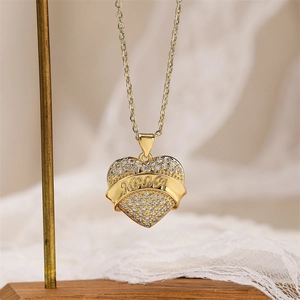 Close-up of gold heart pendant with MAMA engraving and zircon pavé on a metal stand
