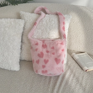 Close-up of pink faux fur tote bag featuring red heart patterns on a soft sofa