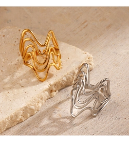 Detailed view of layered 18K gold and silver wavy stackable rings on stone background