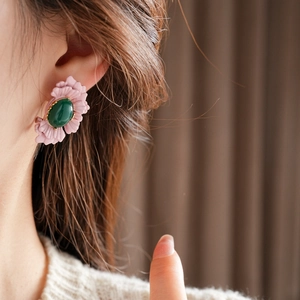 Close-up of vintage flower earrings with pink petals and green stone on female model