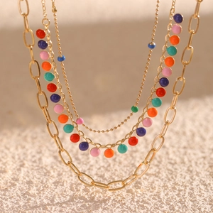 Detail of multi-layer gold chain necklace with colorful enamel charms on white texture