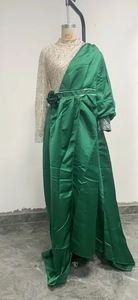 Detail of emerald green satin evening gown with silver sequins and waist flower