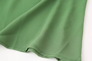 Détail de la texture du tissu en maille verte et de la couture de l'ourlet de la robe