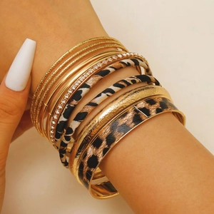 Detail of stacked gold bangles with leopard print elements and rhinestone inlays
