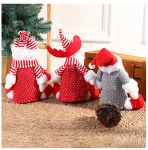 Three festive Christmas plush figures on a straw mat with holiday tree background