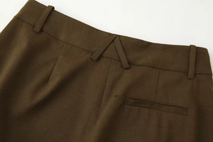 Détail du pantalon plissé marron foncé montrant la taille arrière et la texture du tissu