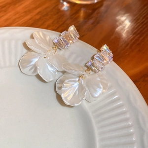 Detail of shell flower tassel earrings with crystals and gold-plated finish in a dish