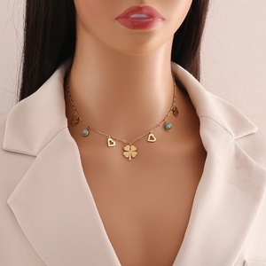 Golden clover and heart necklace with turquoise beads on a woman in a suit