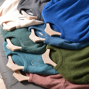 Close-up of stacked colorful knit sweaters in various shades on wooden hangers