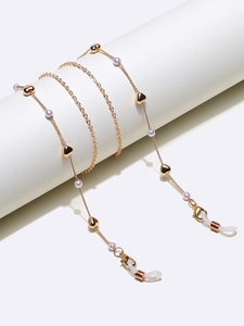 Détail de la chaîne à lunettes dorée avec pendentifs en cœur et perles mauves