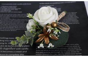 Detail of white PE rose boutonniere with eucalyptus leaves and golden berry accents
