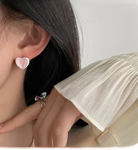 Close-up of pink heart earrings and a silver butterfly ring worn for a sweet look
