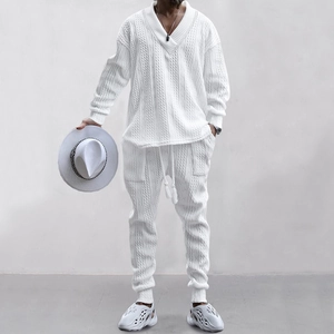 Vollbildansicht eines Mannes in einem weißen Strickset mit V-Ausschnitt und passender Hose.