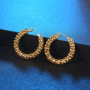 Retro golden hoop earrings with beaded texture on a starry dark background