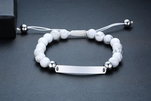 Verstellbares Armband mit weißen Onyx-Perlen und silberner Gravurplatte auf schwarzem Grund