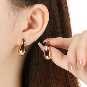 Detailed view of polished rose gold teardrop earrings showing fit and size on model