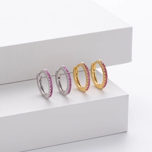 Detail view of gold and silver hoop earrings featuring pavé-set pink crystals