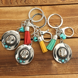 Bohemian alloy cowboy hat keychain with turquoise bead and colorful tassels on wood
