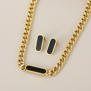 Detailed flat lay of 18K gold plated Cuban chain necklace and matching black stud earrings