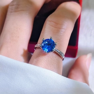 Close-up of a blue ruby ring featuring a silver six-prong setting on a finger