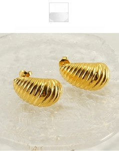 Detail of vintage 18K gold plated spiral earrings with textured swirl on a glass tray