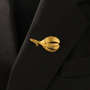 Detail of a golden leaf brooch with radial stripes on a black blazer lapel