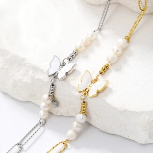 Macro shot of 14K gold butterfly pendant with pearls on a textured white stone base
