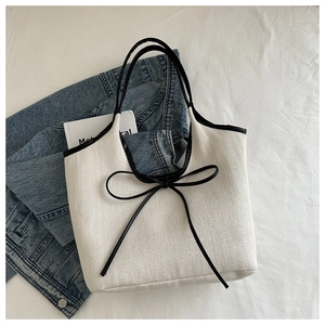 Détail du sac cabas en toile avec texture à chevrons et ruban décoratif noir