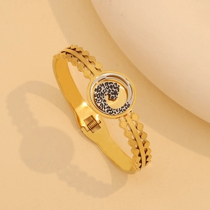 Dettaglio di un bracciale dorato ondulato con un ornamento centrale a macchia di leopardo