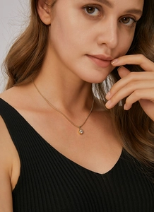 Close-up of minimalist gold beaded necklace with a round sparkling cubic zirconia pendant