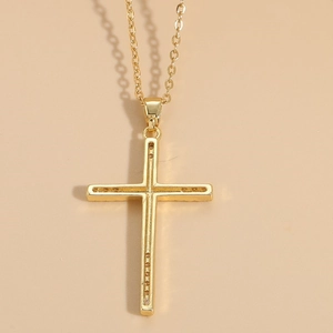 Detail of 14K gold plated zircon cross necklace with delicate cable chain and bow accent