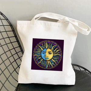 Canvas tote bag with sun and moon art print on a metal chair, bohemian aesthetic style