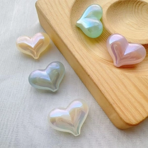Macro detail of heart-shaped pearlescent DIY beads in assorted colors on wooden base