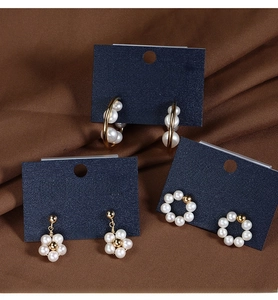 Macro detail of three pearl earring styles on a card with 925 silver needle certification