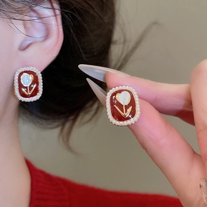 Close-up of vintage red enamel tulip earrings with pearls and gold floral detailing
