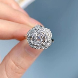 Close-up of S925 silver camellia flower ring with pavé diamonds held in hand