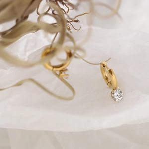 Detail of 18K gold plated hoop earrings featuring sparkling clear round gemstone drops